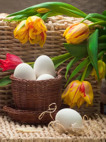 Białe jaja i tulipany wiosna z koszem na słoma taca — Zdjęcie stockowe