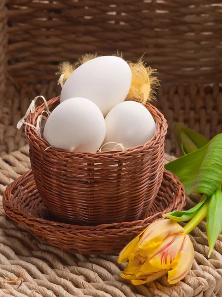 Ovos brancos em pequena cesta marrom na bandeja de palha — Fotografia de Stock