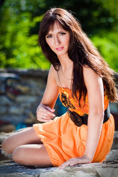 Giovane donna che indossa un abito arancione in un parco — Foto Stock
