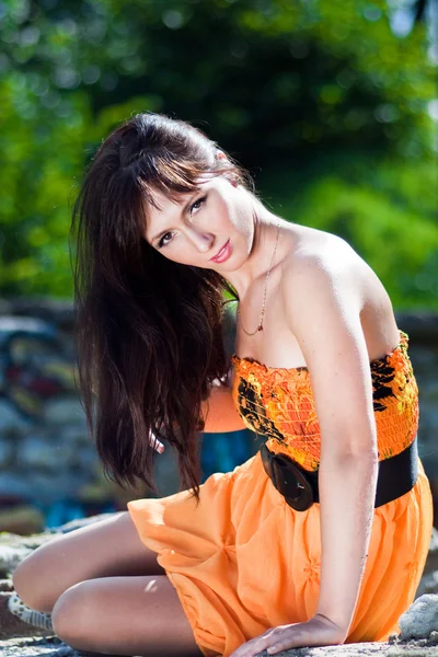 Giovane donna che indossa un abito arancione in un parco — Foto Stock