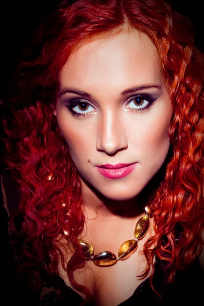 Крупним планом портрет дівчини з червоним кучерявим волоссям у бурштиновому намисті на блакитному — стокове фото