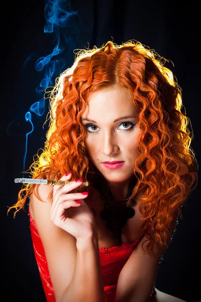 Sexy chica con el pelo rojo usando corsé rojo sosteniendo boquilla ámbar en blac —  Fotos de Stock