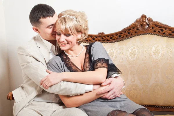 Счастливые невеста и жених на древнем диване с резьбой — стоковое фото