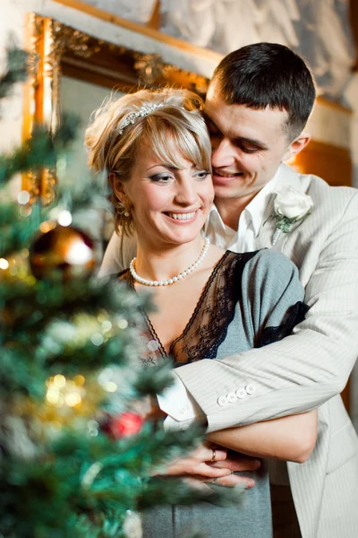 Bride and groom in interior near christmas tree — Stock Photo, Image
