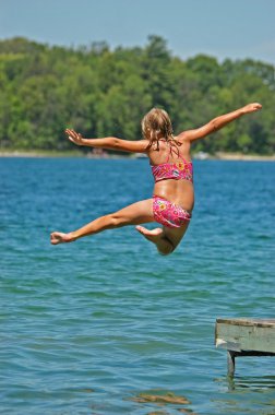 Young Girl Jumps Off Dock with Arms and One Leg Spread clipart