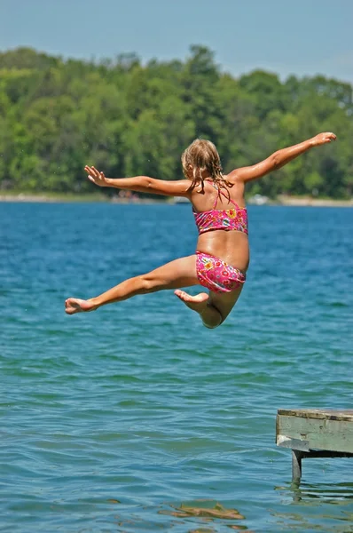 Joven chica salta de muelle con brazos y una pierna extendida —  Fotos de Stock