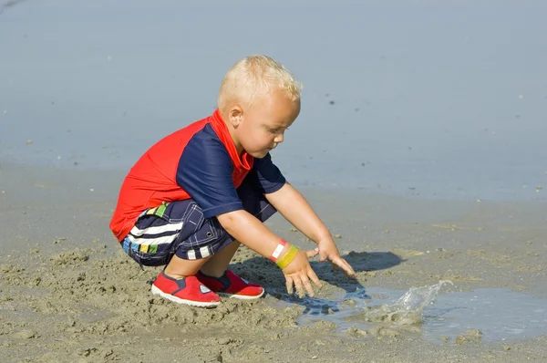 Pojke spelar i sanden på stranden — Stockfoto