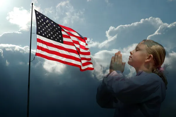 女の子のアメリカ国旗の嵐の空を祈ってください。 — ストック写真