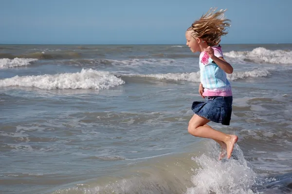 Młoda dziewczyna skacze w surf — Zdjęcie stockowe