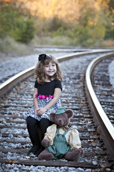 Маленька дівчинка і плюшевий ведмідь на залізничних коліях — стокове фото