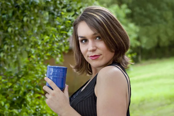 Linda morena segurando xícara de café ao ar livre — Fotografia de Stock