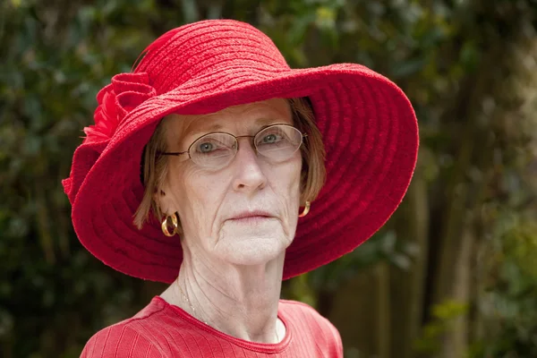 Beautiful mature woman outdoors in red hat — Stock Photo, Image