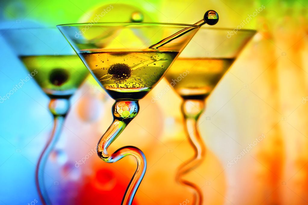 Beautiful martini glasses with olives in front of colorful background showing colors of red, orange, blue and green