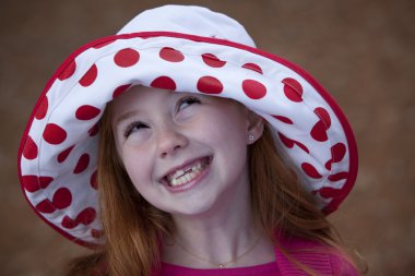 Cute little redhead in hat outdoors clipart