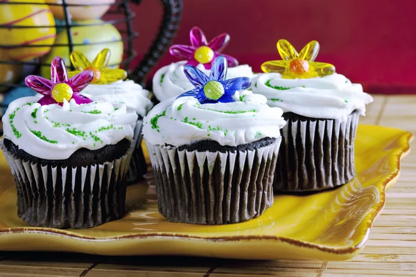 Cupcakes with sprinkles and plastic flowers — Stock Photo, Image
