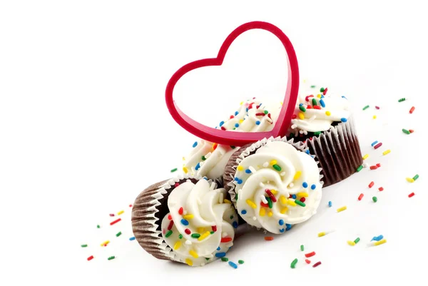 Chocolade cupcakes met witte berijpen hagelslag en hart Stockfoto