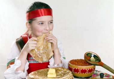 Russian girl behind a table with pancakes clipart