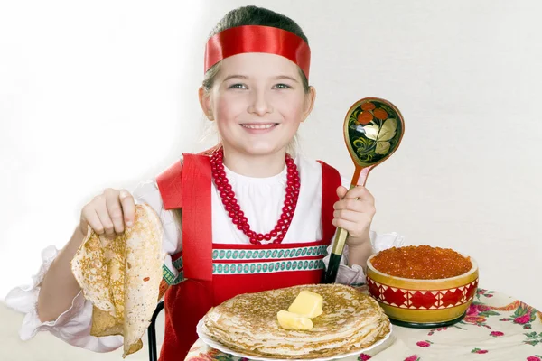 Russisch meisje achter een tafel met pannenkoeken — Stockfoto
