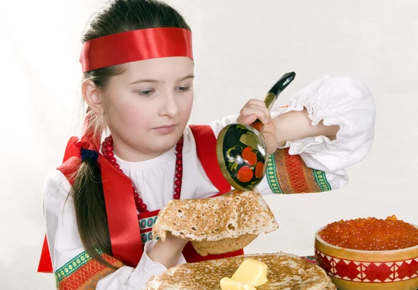 Russian girl behind a table with pancakes — Stock Photo, Image