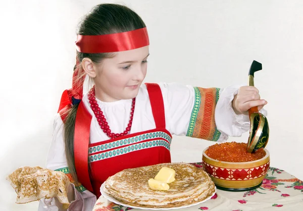 Русская девушка за столом с блинчиками — стоковое фото