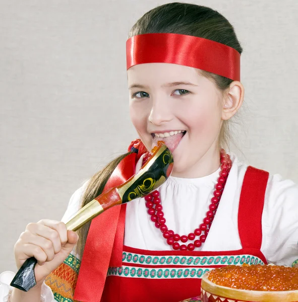 Menina lambe uma colher com caviar vermelho — Fotografia de Stock