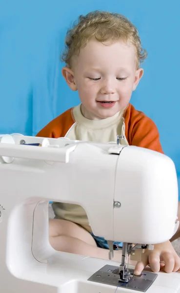 Красный мальчик и швейная машинка — стоковое фото
