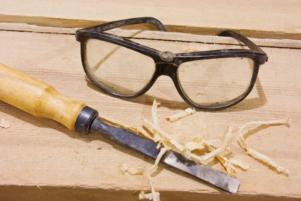 Защитные очки и долото на деревянном столе — стоковое фото