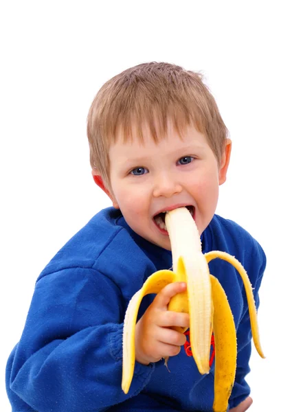 Un enfant souriant mange de la banane Image En Vente