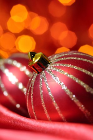 Boules décoratives de Noël sur soie rouge contre les lumières floues sur 