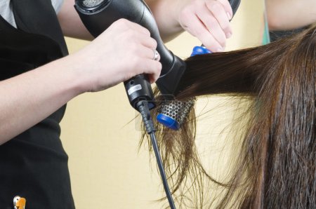 gros plan de fille tête dans salon de beauté tandis qu'un coiffeur brosse et sèche ses cheveux 